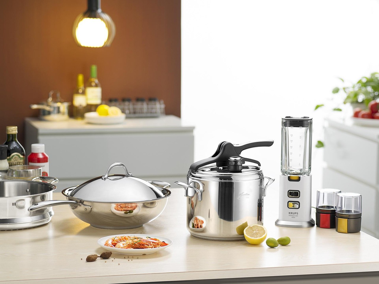 Autocuiseur en inox posé sur un plan de travail de cuisine à côté d'un wok et d'un mixeur