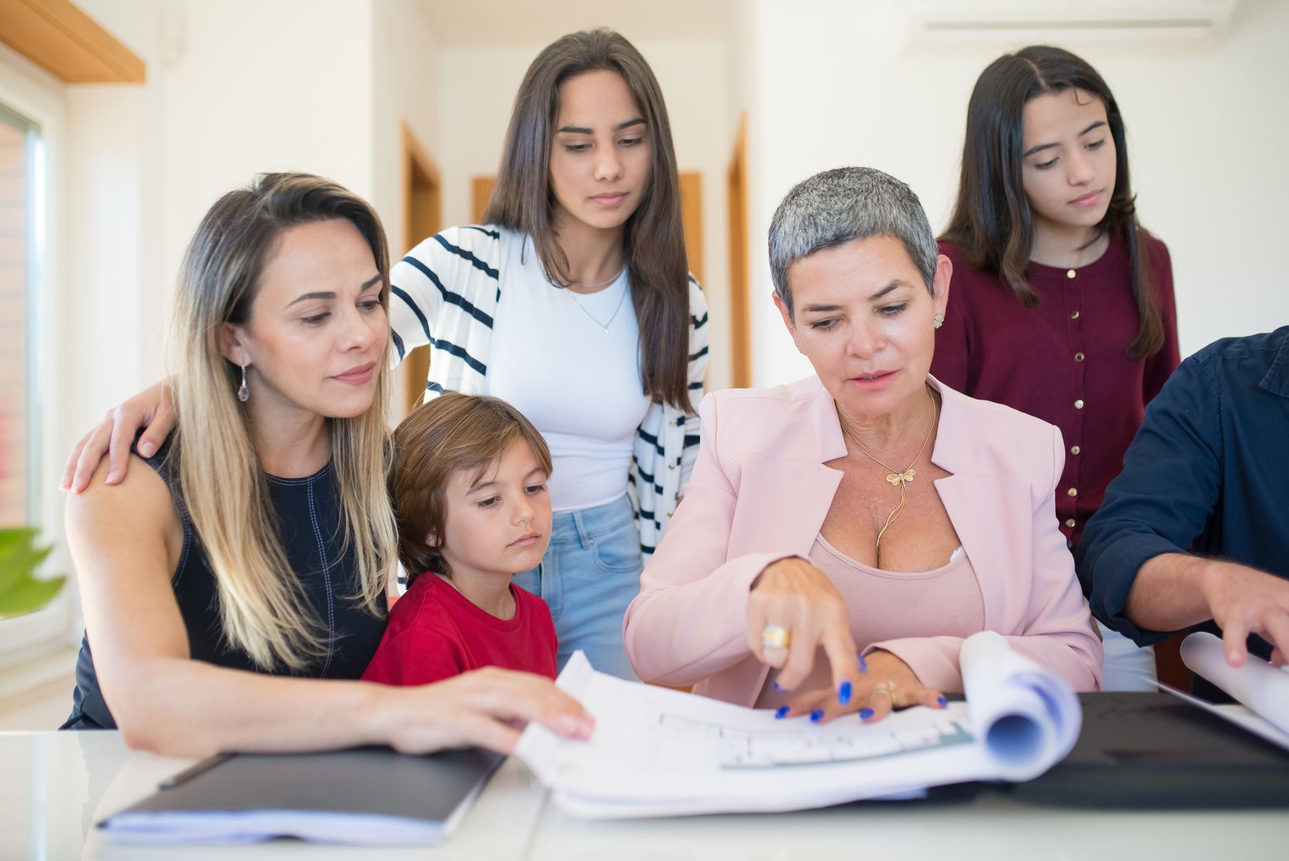Une famille avec des enfants penchée sur des documents administratifs posés sur une table
