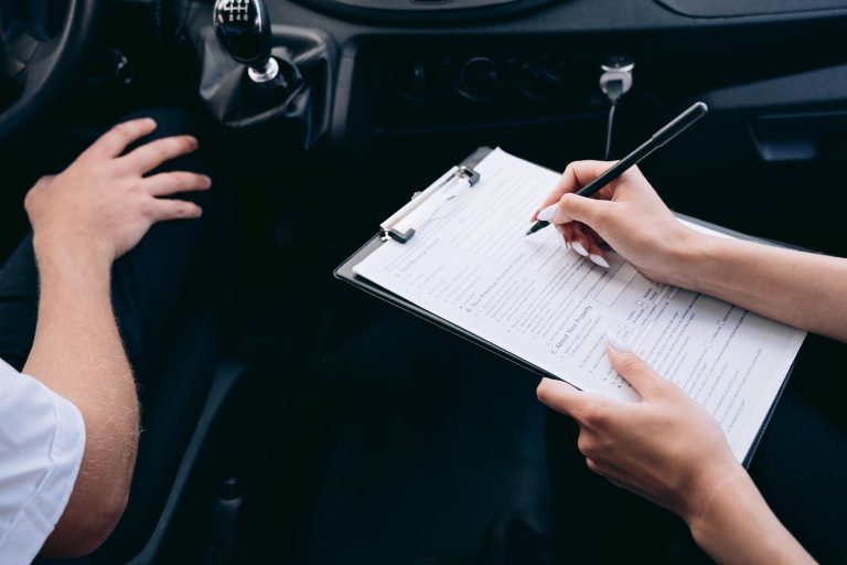 Mains remplissant un formulaire sur une planchette dans l'habitacle d'une voiture