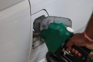 Main tenant un pistolet de pompe vert dans le réservoir d'une voiture blanche, gros plan