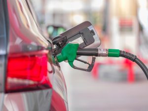 Pistolet de pompe vert inséré dans le réservoir d'une voiture aux feux arrière rouges
