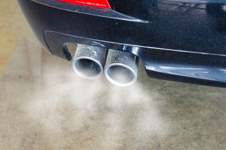 Gros plan sur le double pot d'échappement d'une voiture qui rejette de la fumée