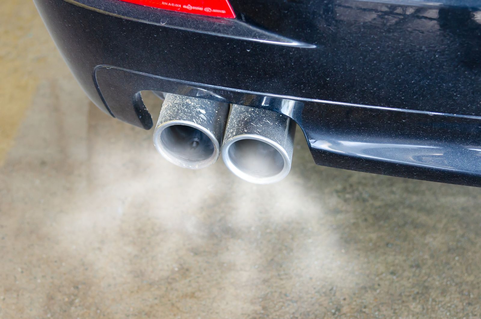 Gros plan sur le double pot d'échappement d'une voiture qui rejette de la fumée