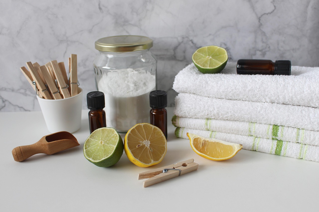 Produits d'entretien naturels : bicarbonate de soude, citrons, huiles essentielles, pinces à linge en bois et linges blancs pliés