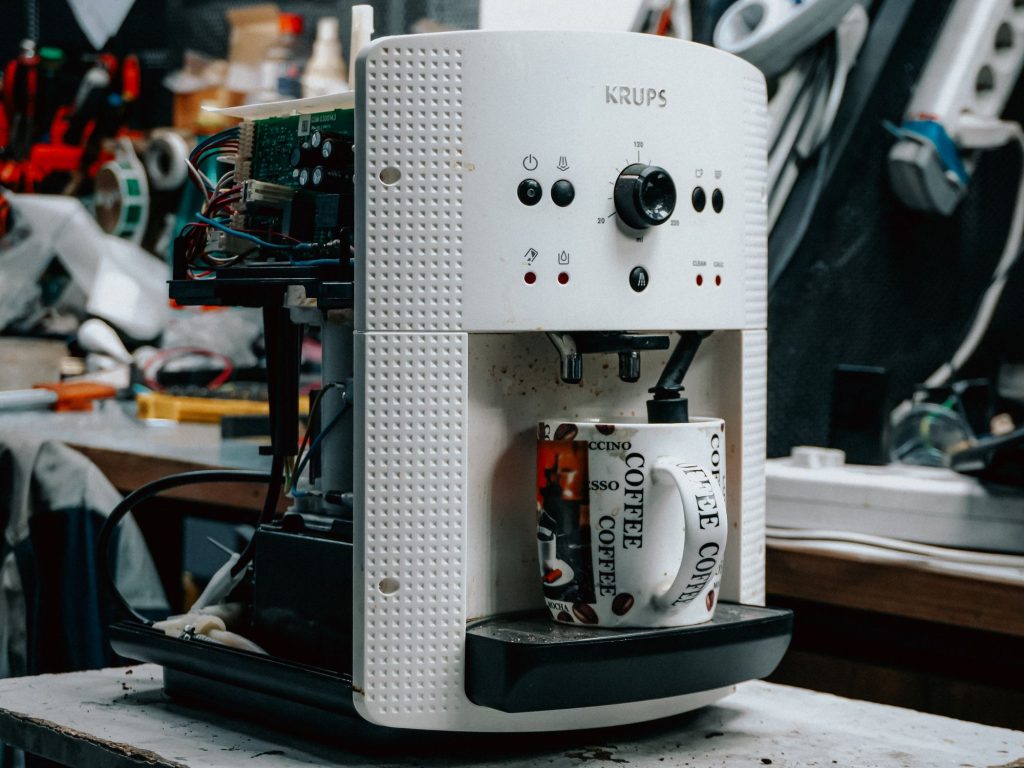 Cafetière électrique en cours de réparation sur un établi, composants électroniques apparents