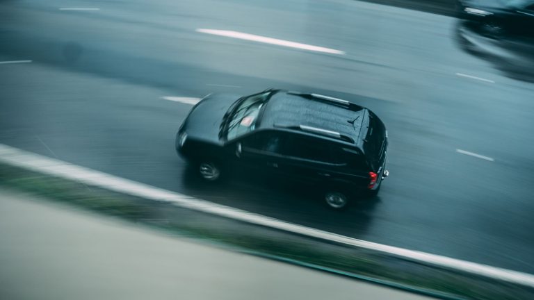 SUV sombre vu de dessus roulant sur une route, effet de vitesse
