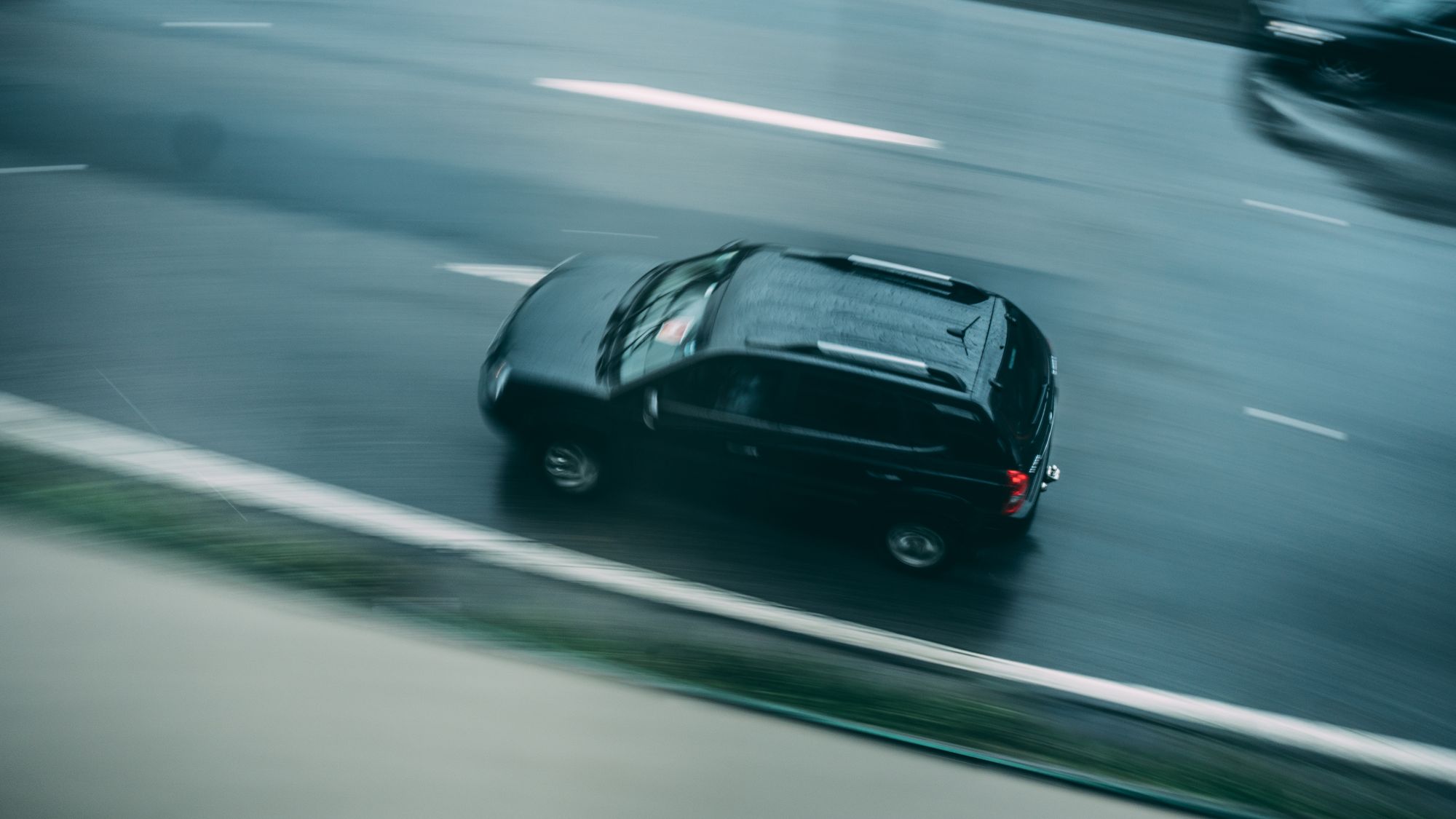 SUV sombre vu de dessus roulant sur une route, effet de vitesse