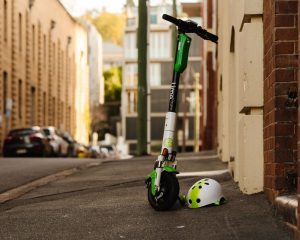 Trottinette électrique et casque blanc posés contre un mur dans une ruelle