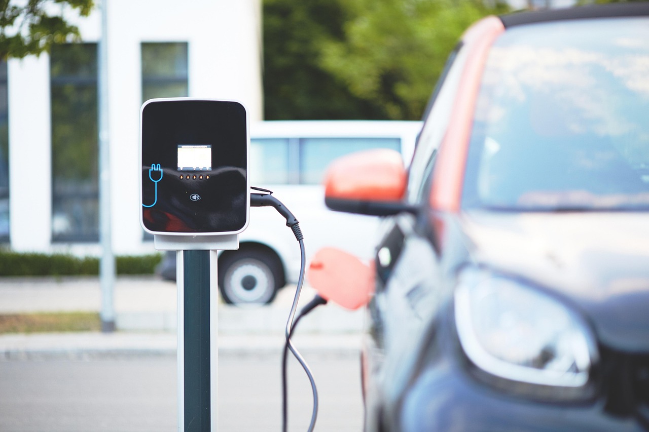 Une voiture électrique de ville branchée sur une borne de recharge murale sur un parking