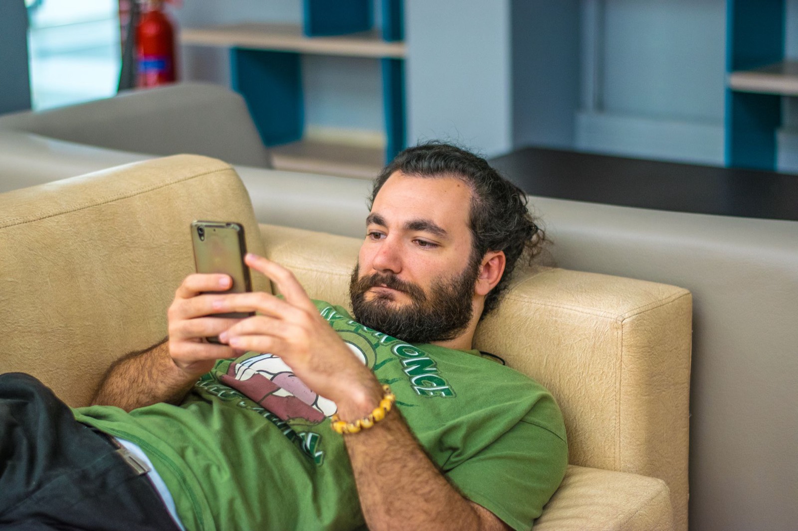 Supporter qui consulte les scores de football en direct sur son smartphone, installé dans un canapé
