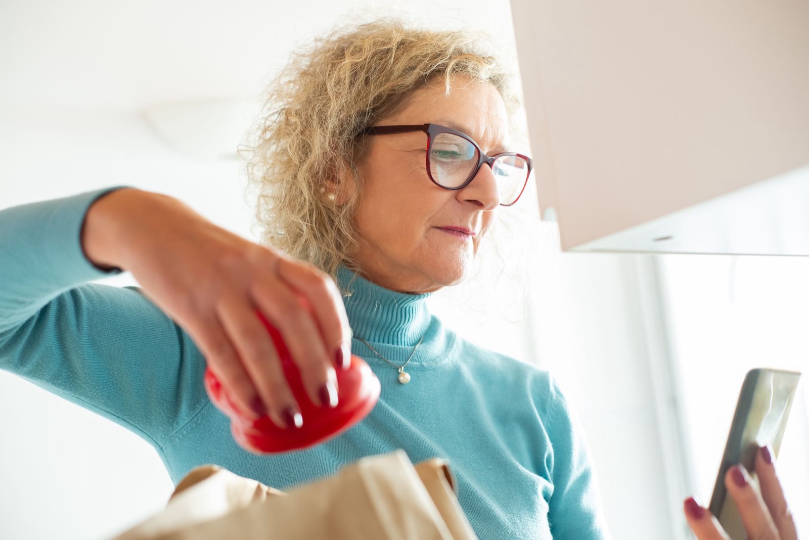 Une femme vérifie sa liste de courses sur son smartphone dans la cuisine