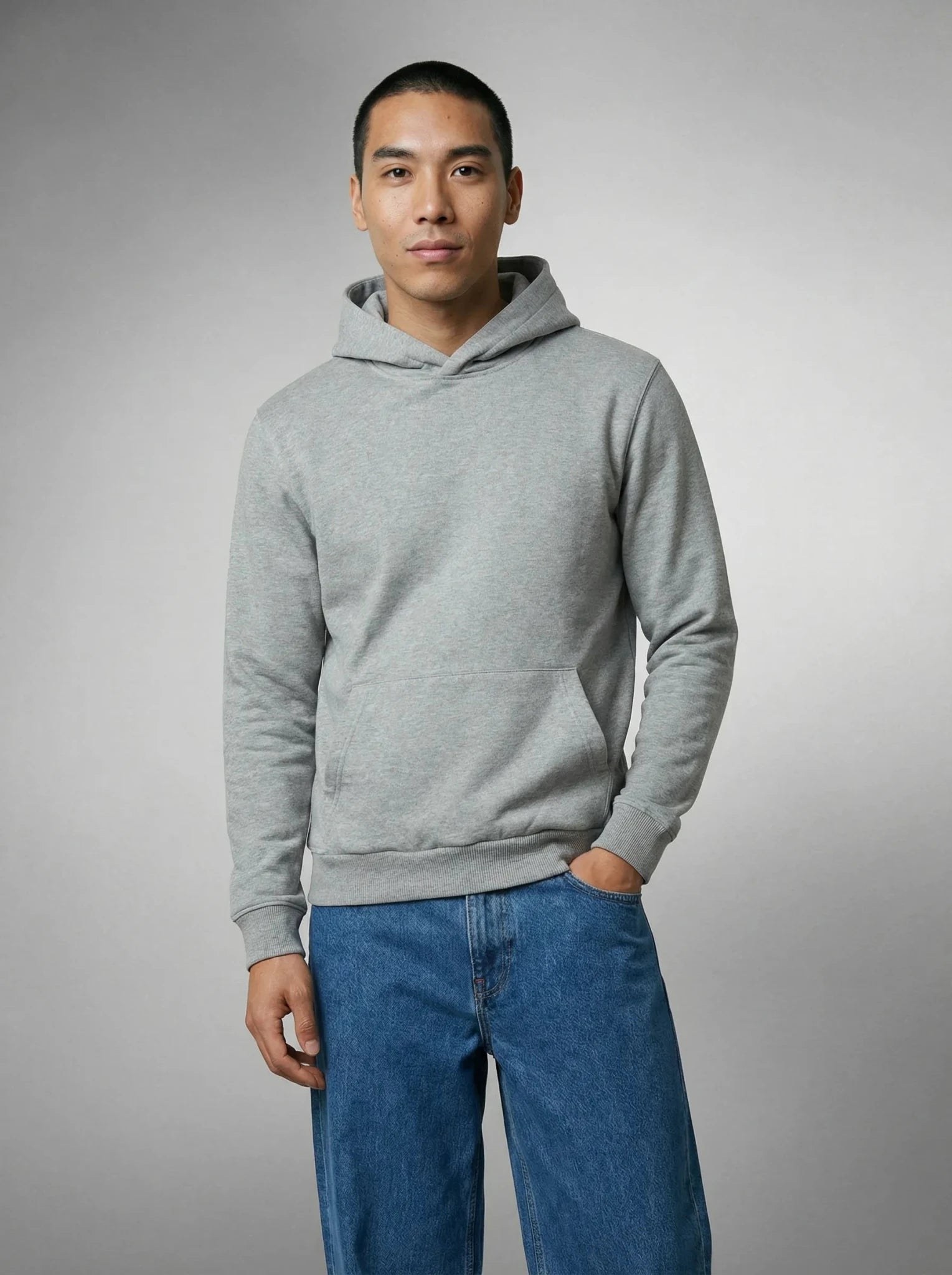 Homme en sweat à capuche gris, main dans la poche, posant de face